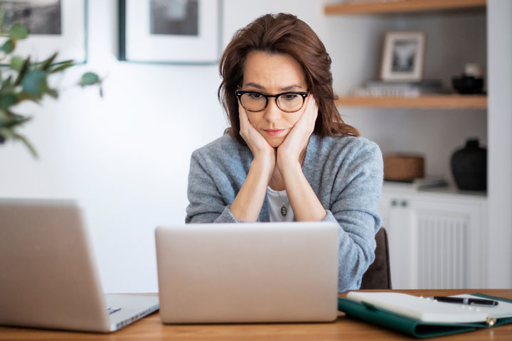 Worried,Woman,Sitting,At,Laptops,And,Hands,On,Face.,Careworn